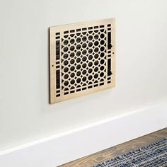 a wooden grate mounted on the wall above a blue rug