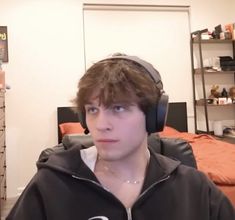 a young man wearing headphones while sitting in front of a bed