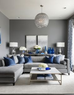 a living room with gray walls and blue accents on the couches, coffee table and lamps