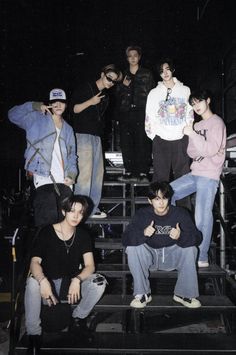 a group of young men sitting on top of steps in front of a crowd at night