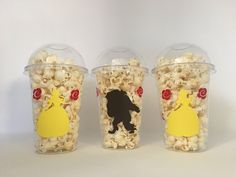 three plastic cups filled with popcorn and one has a black bear on the side,