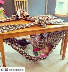 a baby sitting in a hammock under a table