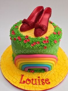 a cake decorated with grass, flowers and red shoes on top of it that says louise