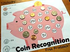 a pink piggy bank sitting on top of a wooden table next to some coins