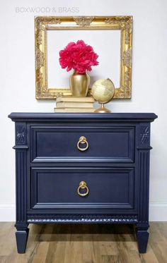 a blue dresser with two drawers and a red flower on top in front of a mirror