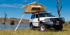 an suv parked next to a body of water with a tent on it's roof