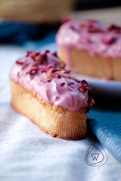 two pastries sitting on top of a table next to each other with pink frosting