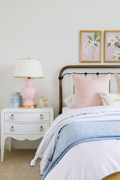 a bedroom with two pictures on the wall above the bed and nightstand next to it