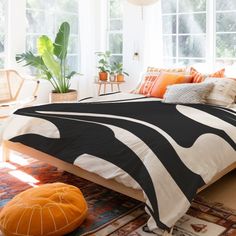 a bed room with a neatly made bed and lots of plants in the window sill