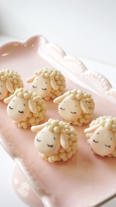 some little sheep are sitting on a pink tray