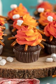 chocolate cupcakes decorated with orange and white frosting on a wooden platter