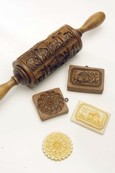 a wooden rolling pin and some rubber stamps on a white surface with an ornate design