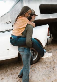 a man carrying a woman on his back in front of a truck