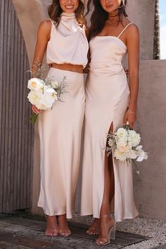 two women standing next to each other wearing matching dresses and holding bouquets in their hands