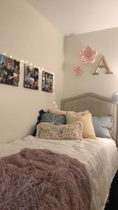 a white bed topped with lots of pillows next to pictures on the wall above it