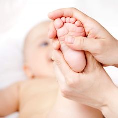 a woman is holding the foot of a baby's foot in her hands while laying down