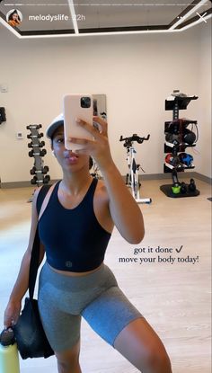 a woman taking a selfie in a gym with her cell phone and water bottle