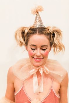 a woman wearing a party hat and tutu with her hair in pigtails is smiling