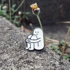 a small white sticker sitting on top of a rock next to a yellow flower