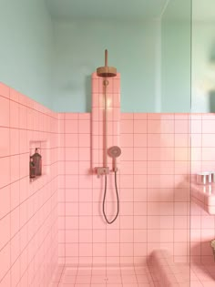 a pink tiled bathroom with a shower head and hand held shower faucet in the corner