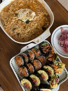 an assortment of sushi and rice dishes on a wooden table with chopsticks