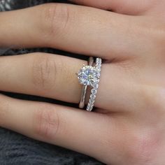 a woman's hand with a diamond ring on top of her finger and an engagement band