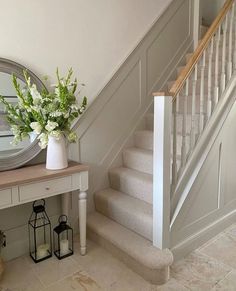 a white vase with flowers sitting on top of a table next to a stair case