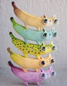 five bananas with cats on them and one banana in the middle, all different colors