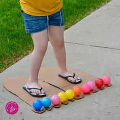 a child standing on top of a mat with colorful balls