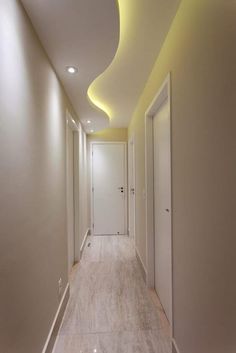 a long hallway with white walls and ceiling lights on either side of the corridor is lit by recessed lighting