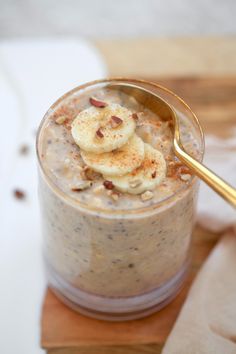 a glass with some food in it on a wooden board and a spoon next to it