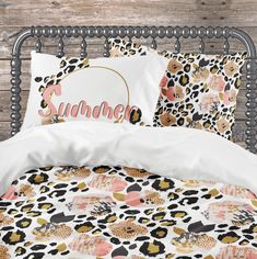 a bed topped with pillows and blankets covered in animal print next to a wooden wall