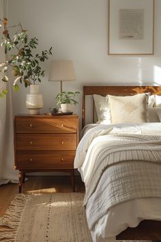 a bedroom with a bed, dresser and plant in it on the side table next to the window