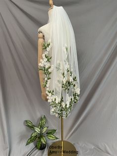 a mannequin wearing a white veil with flowers on it next to a sign