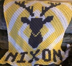 a crocheted blanket with an image of a deer on it and another animal laying next to it