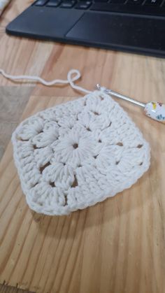 a crocheted doily sitting on top of a wooden table next to a laptop computer