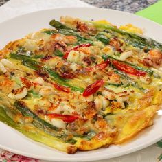 a white plate topped with an omelet covered in veggies