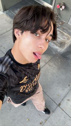 a young man sticking his tongue out on the sidewalk