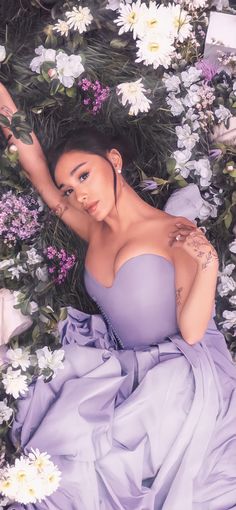 a woman laying on the ground surrounded by white and purple flowers with her arms stretched out