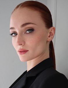 a woman with red hair and blue eyes wearing a black shirt looking at the camera