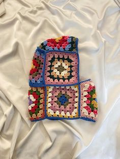 two crocheted squares are laying on top of each other in the middle of a white sheet