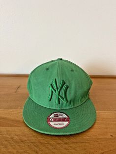 a green new york yankees hat sitting on top of a wooden table