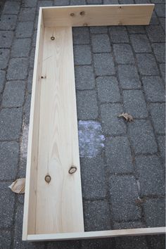 a wooden bench sitting on top of a brick road next to a sidewalk with no one around it