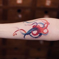 an octopus tattoo is on the arm of a woman's arm and it looks like she has something in her mouth