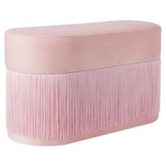 a pink ottoman with fringes on the top and bottom, sitting in front of a white background