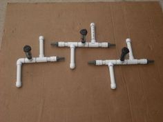 four white pipes connected to each other on top of a brown cardboard box with screws and wrenches