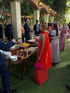 a man in a suit and tie serving food to people at an outdoor event on grass