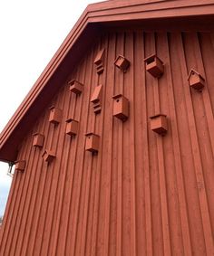 the side of a red building with small birdhouses on it