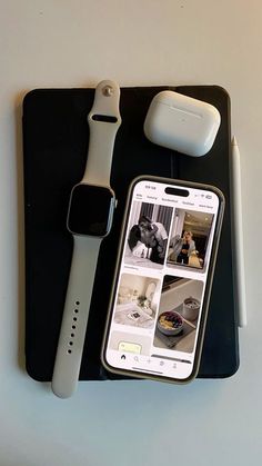 an apple watch, cell phone and other electronics on a black tray next to each other