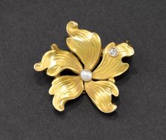 Offered is a beautiful, dainty and petite Art Nouveau period gold flower brooch pin in lovely original condition. Finely made in 14K yellow gold, the piece retains most of its original bloomed finish with the characteristic matte surface so popular at the time.  At its center rests a lustrous creamy pearl, and a tiny but fiery old mine cut diamond sparkles like a spot of dew on one petal. The small size of this pretty pin makes it quite versatile.  It measures approximately 7/8 of an inch in dia Formal Flower Shaped Hallmarked Brooch, Classic Flower Brooches For Anniversary, Wedding Flower Brooch Hallmarked, Flower Shaped Wedding Brooches Hallmarked, Wedding Flower Brooches Hallmarked, Formal Fine Jewelry Gold Brooches, Flower Shaped Wedding Brooches, Gold Flower Brooch For Formal Occasions, Elegant Gold Flower Brooch